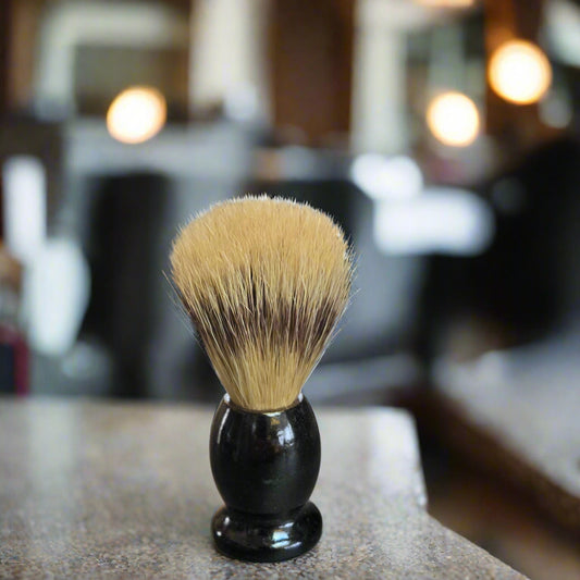 Shaving brush with black handle and bristle head on a metallic surface
